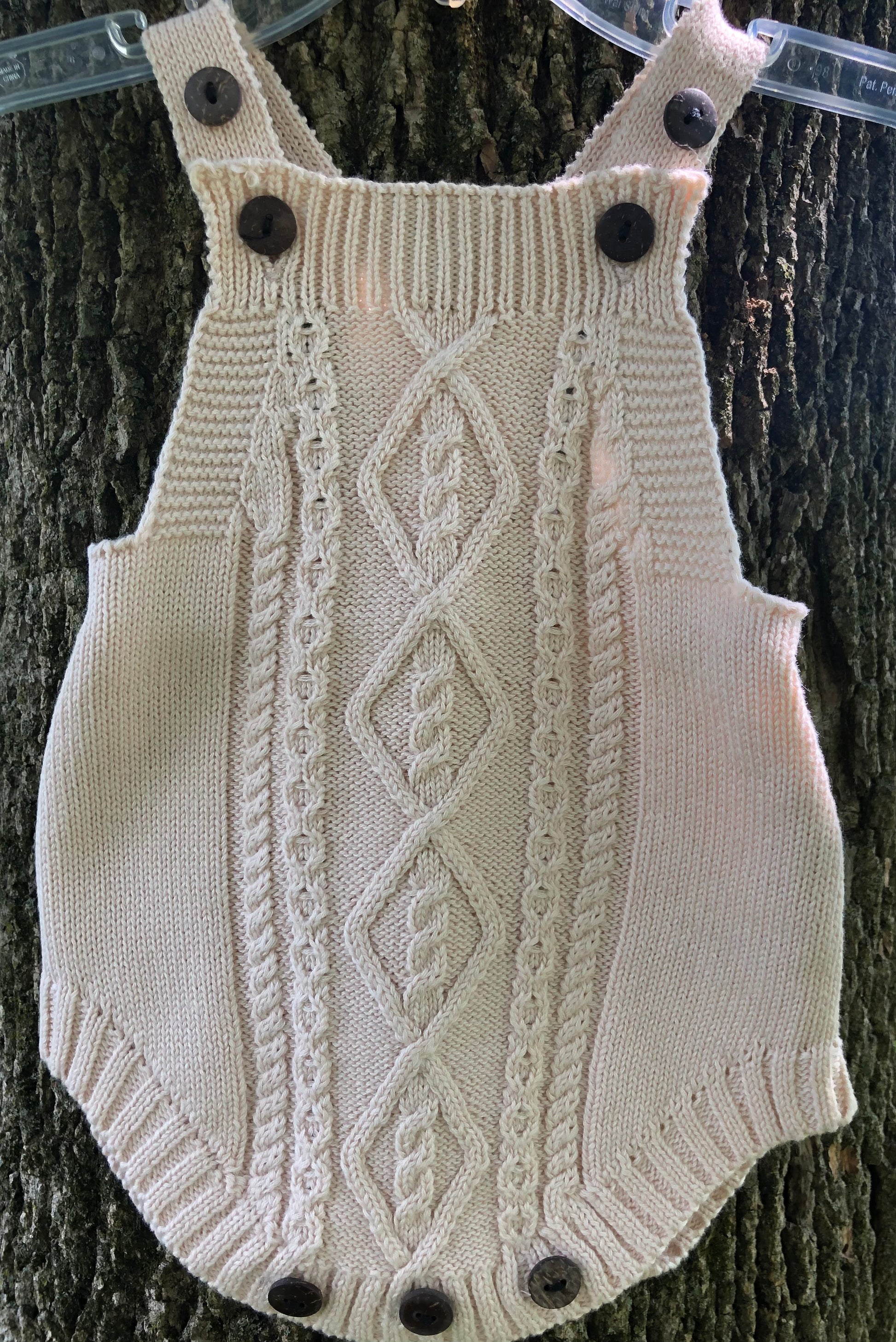 knit cotton baby romper in cream with tree in background